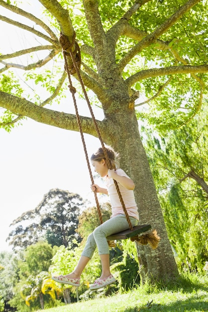 Niña sentada en el columpio en el parque