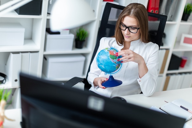 Una niña sentada en una computadora Escritorio en la oficina y sosteniendo un globo.