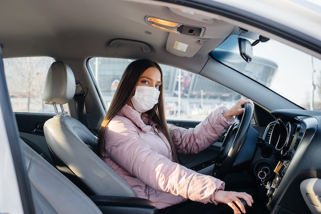 Una niña sentada detrás del volante en el coche con máscara