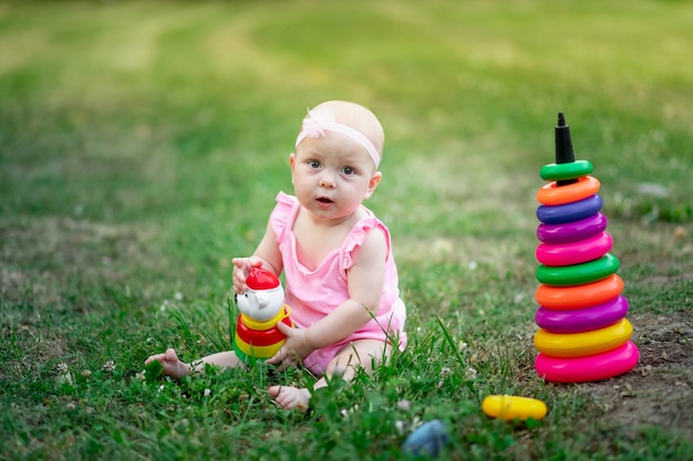 niña sentada en la hierba en el verano y jugando pirámide