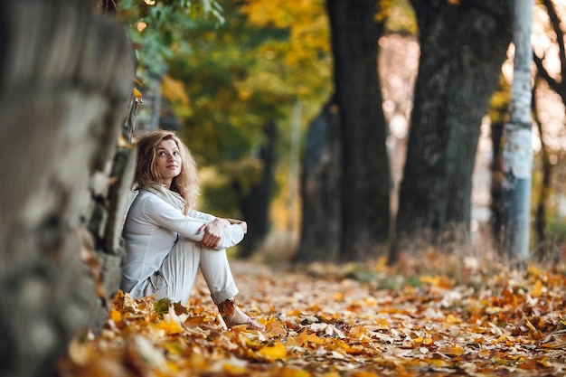 Foto niña sentada en hojas de otoño