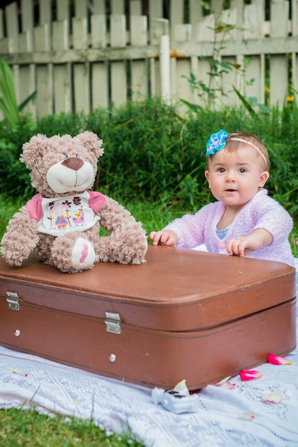 Niña sentada junto a la maleta