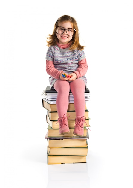 Niña sentada en libros. De vuelta a la escuela