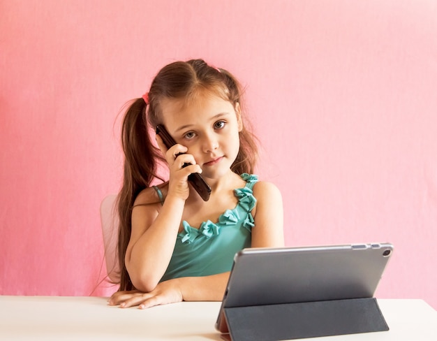 Niña sentada en la mesa y hablando por teléfono