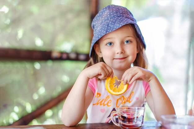 niña sentada en una mesa en el jardín de verano