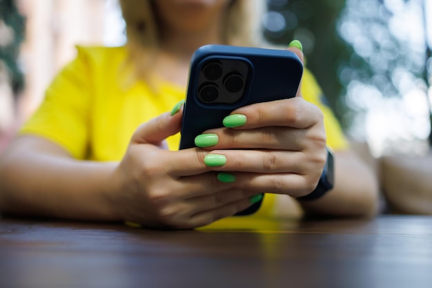 Una niña sentada en una mesa con un teléfono en las manos.