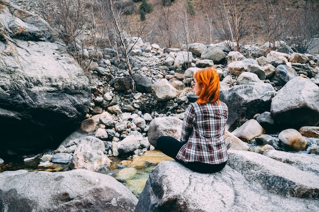 La niña sentada en la montaña de roca.