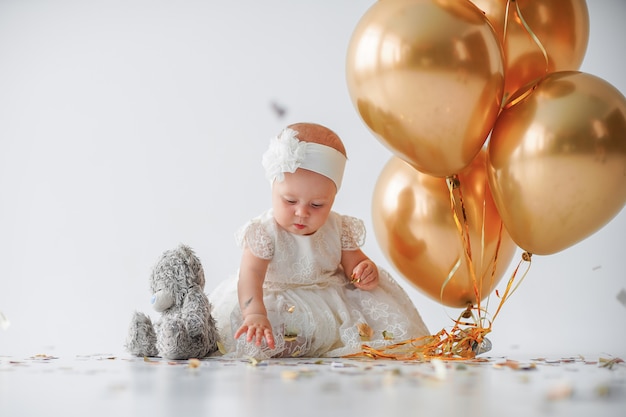 Niña sentada con un montón de globos dorados