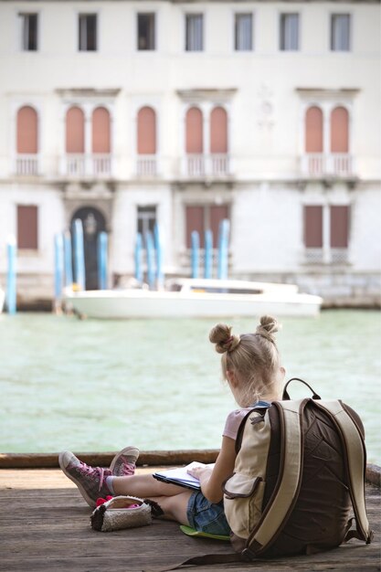 Foto niña sentada en un muelle en venecia, italia