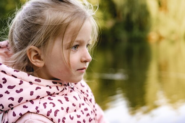 Niña sentada en el parque cerca del lago