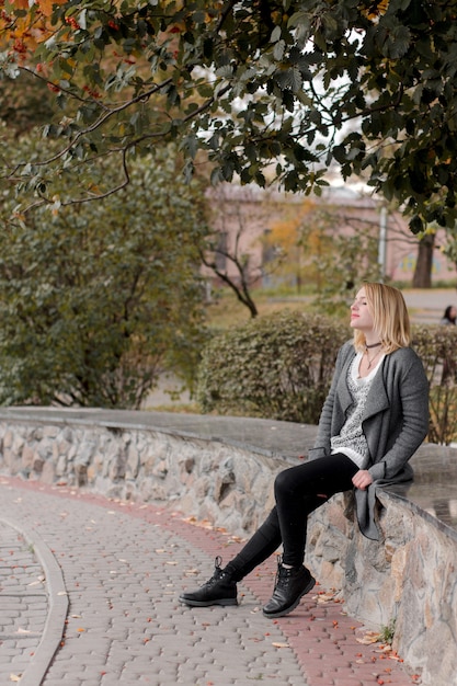 Niña sentada en el parque otoño