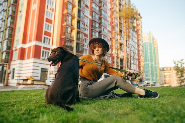 Niña sentada en el patio en el césped con un perro con una correa