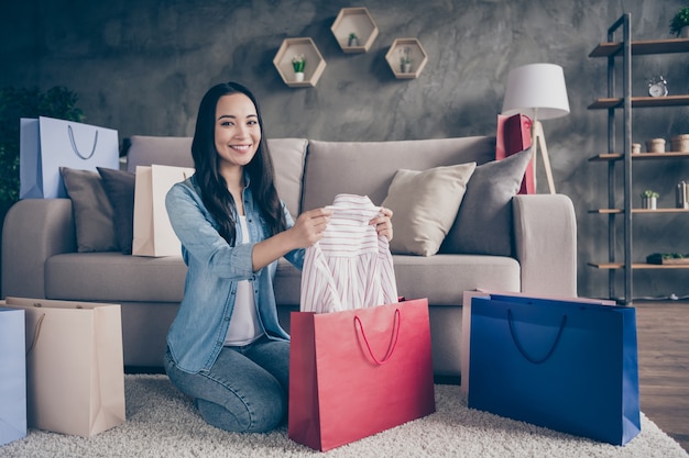 niña sentada en el piso con bolsas de compras