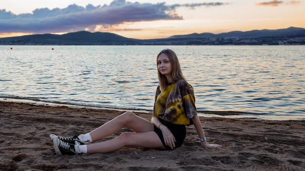 Una niña sentada en una playa de arena