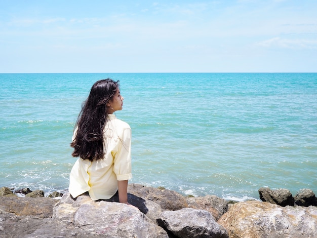 niña sentada en las rocas en la playa.