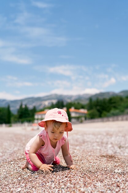 Niña sentada de rodillas en la playa y cava un agujero villa milocer montenegro