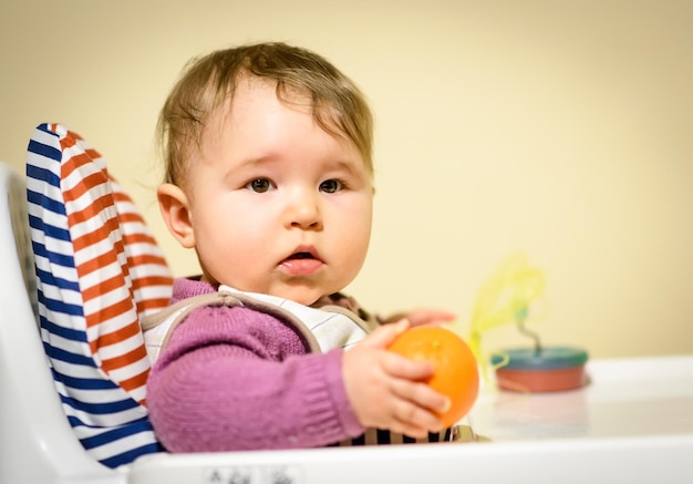 Niña sentada en una silla de bebé en la cocina