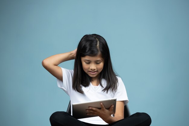 niña sentada en una silla mirando tablet