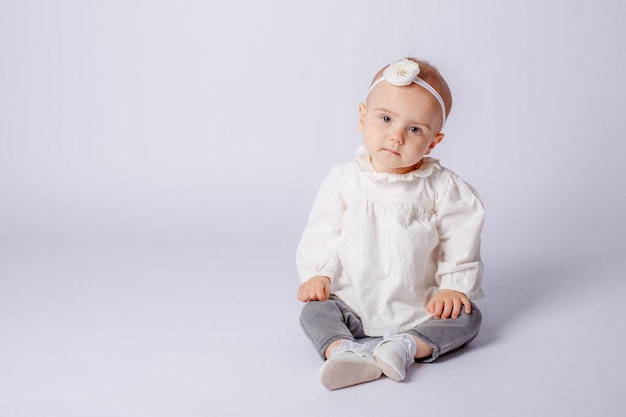 Niña sentada sobre un fondo blanco aislado