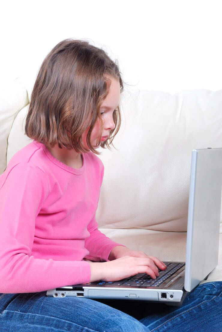 Foto niña sentada en el sofá y usando laptop