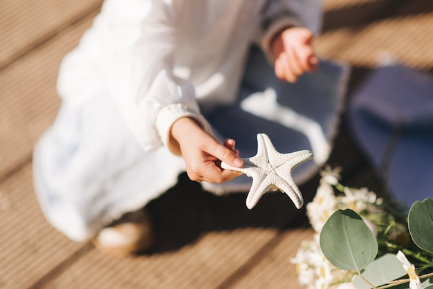 Niña sentada y sosteniendo una estrella de mar verano y niños