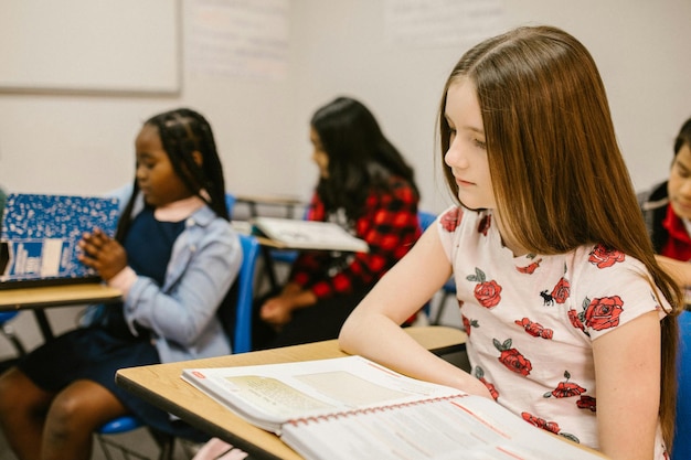 Niña sentada en su escritorio mientras estudia Foto