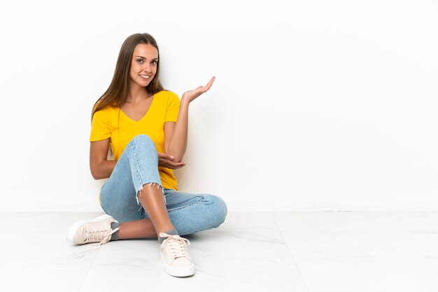 Niña sentada en el suelo extendiendo las manos hacia un lado para invitar a venir