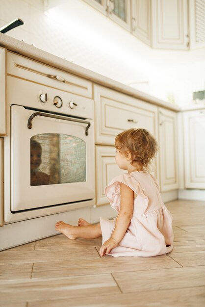 Niña sentada en el suelo en el horno de cocción y mirando el proceso de preparación de los pasteles.