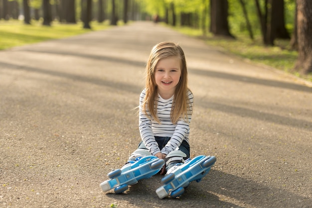 Niña sentada en la tierra, descansando del patinaje