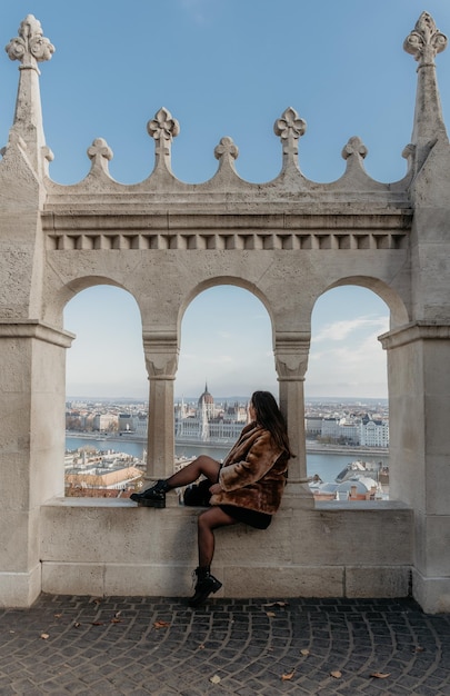 Foto niña sentada en una ventana arqueada en el bastión de los pescadores en budapest, hungría