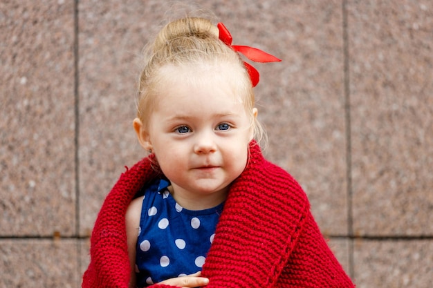 Niña sentada en un vestido azul cubierto con una tela escocesa roja