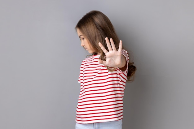 Una niña seria que usa una camiseta que muestra un gesto de parada de bloque retrasa el acoso y la violencia