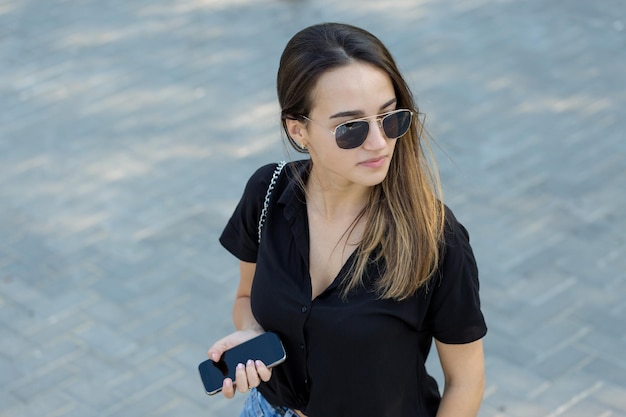 Una niña se sienta en un banco en un parque y toma notas Vestida con un estilo libre Mujer de negocios hablando por teléfono con los clientes