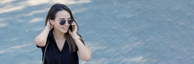 Una niña se sienta en un banco en un parque y toma notas Vestida con un estilo libre Mujer de negocios hablando por teléfono con los clientes