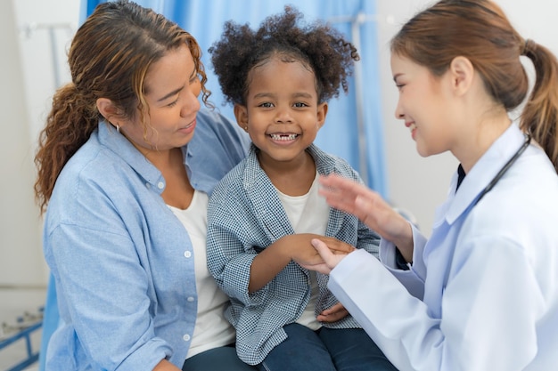 La niña se sienta en la cama del paciente para el médico.