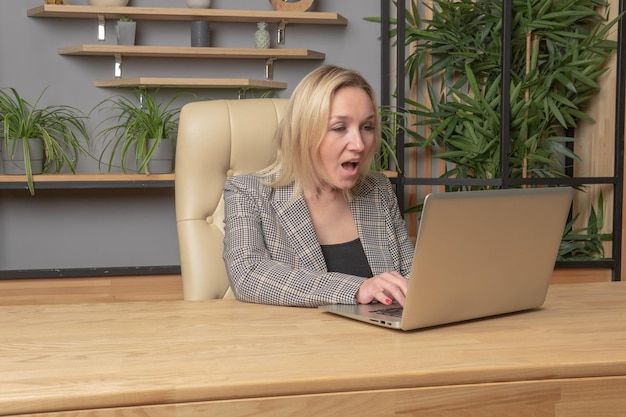 La niña se sienta en la computadora portátil, piensa emocionalmente, una mujer, una computadora portátil de negocios, una persona de tecnología, una mujer en un sitio web, una web académica, un dispositivo bastante moderno que usa un reloj virtual de maqueta.