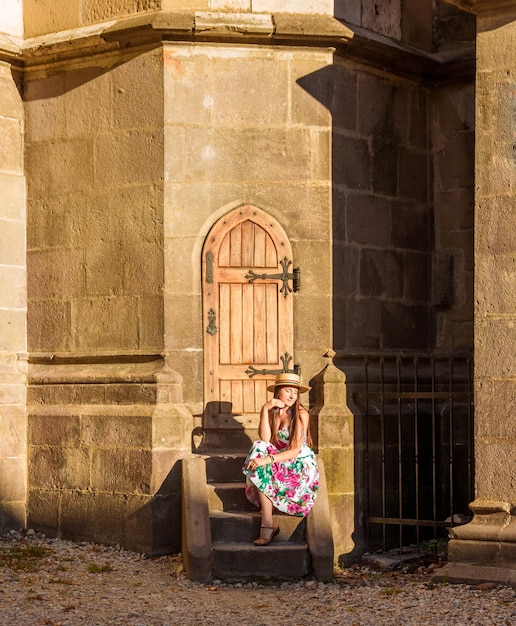 Una niña se sienta en una escalera cerca de la Iglesia Negra en Brasov