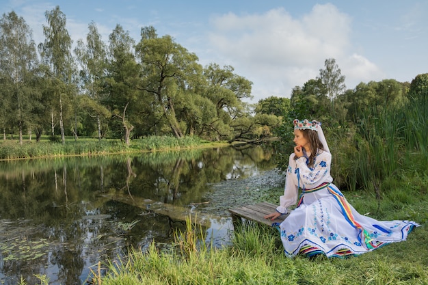 La niña se sienta en el fondo de la naturaleza bielorrusa.