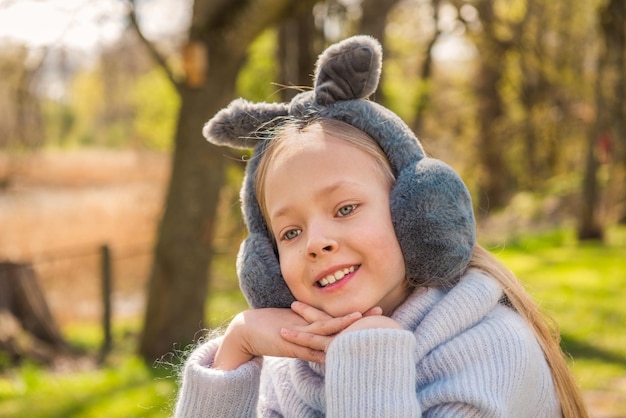 La niña se sienta en un gran tocón en la naturaleza en primavera