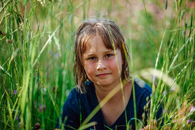 Una niña se sienta en la hierba alta
