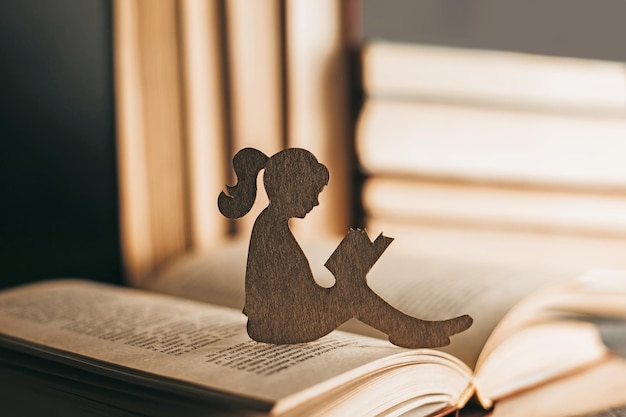 La niña se sienta entre los libros y lee un cuento de hadas Desarrollo intelectual del niño