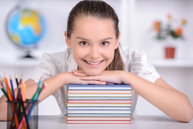 Niña se sienta a la mesa y pone sus manos y cabeza sobre el libro.