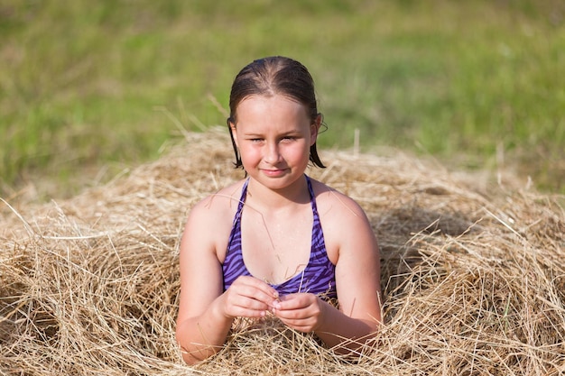 Una niña se sienta en un pajar en un campo