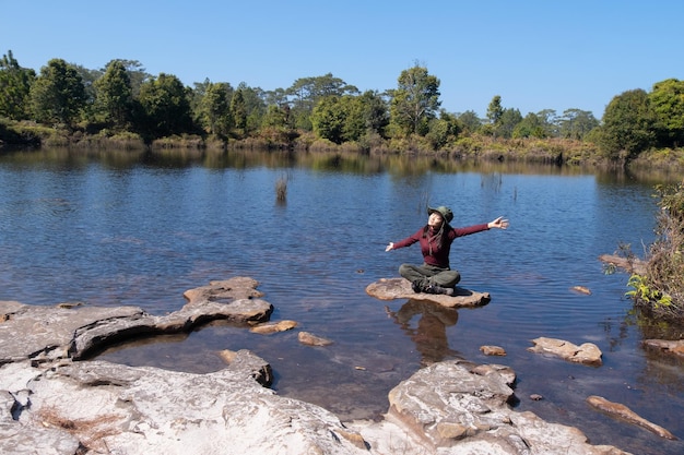 Una niña se sienta en una roca en medio de un estanque en un parque nacional