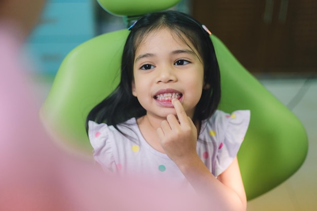 Una niña se sienta en una silla dental y sonríe.