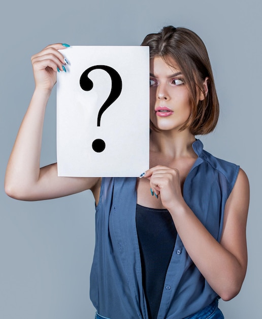 Niña con un signo de pregunta en el papel Mujer anónima Niña dudosa que se hace preguntas a sí misma Notas de papel con signos de pregunta Pensamiento femenino confundido con signos de interrogación