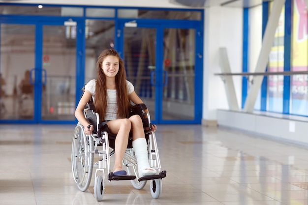 Una niña en silla de ruedas está de pie en el pasillo del hospital.