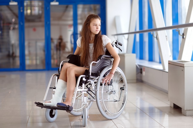 Una niña en silla de ruedas está de pie en el pasillo del hospital.