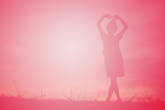 Niña silueta posando en el campo contra el cielo durante la puesta de sol