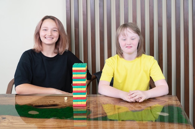 Niña con síndrome de down con su hermana se preparan para jugar el juego de mesa jenga